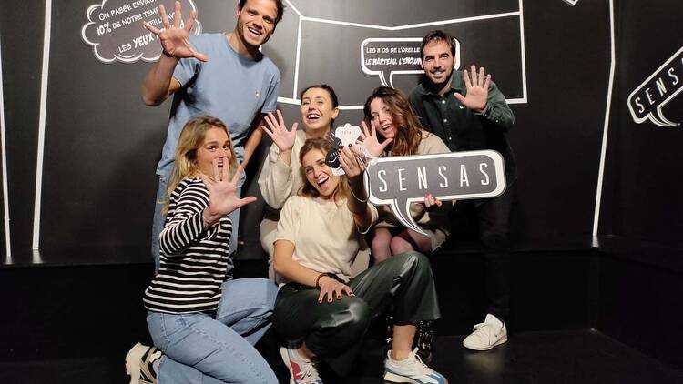 A group of people posing for a photo, holding up five fingers. 