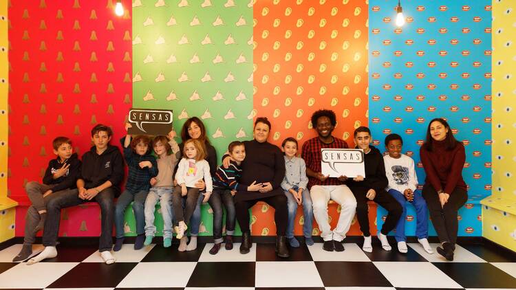 A group of people posing for a photo in front of a rainbow coloured wall. 