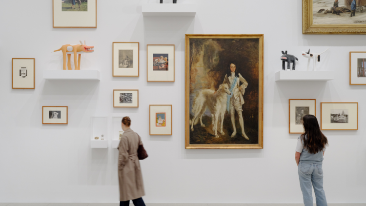 Two people in front of artworks featuring dogs