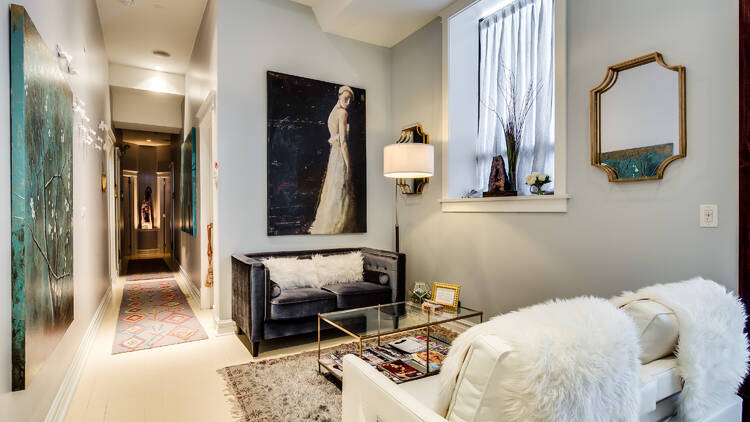 A white lobby area with a couch, rug and paintings on the wall 