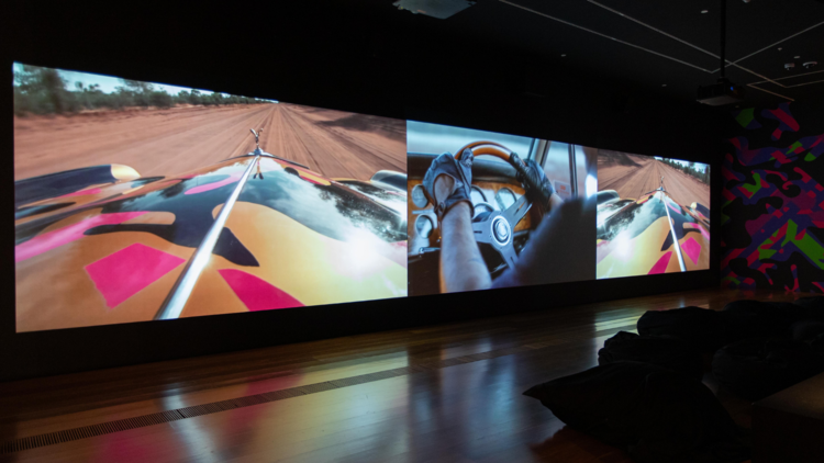 A media room showing Reko Rennie's video driving his custom car