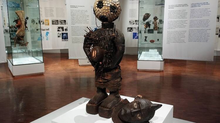 Escultura de Hilaire Balu Kuyangiko, artista congolês nascido em 1992, que aqui se apropria dos objectos de culto ancestrais nkisi, numa crítica ao consumismo global