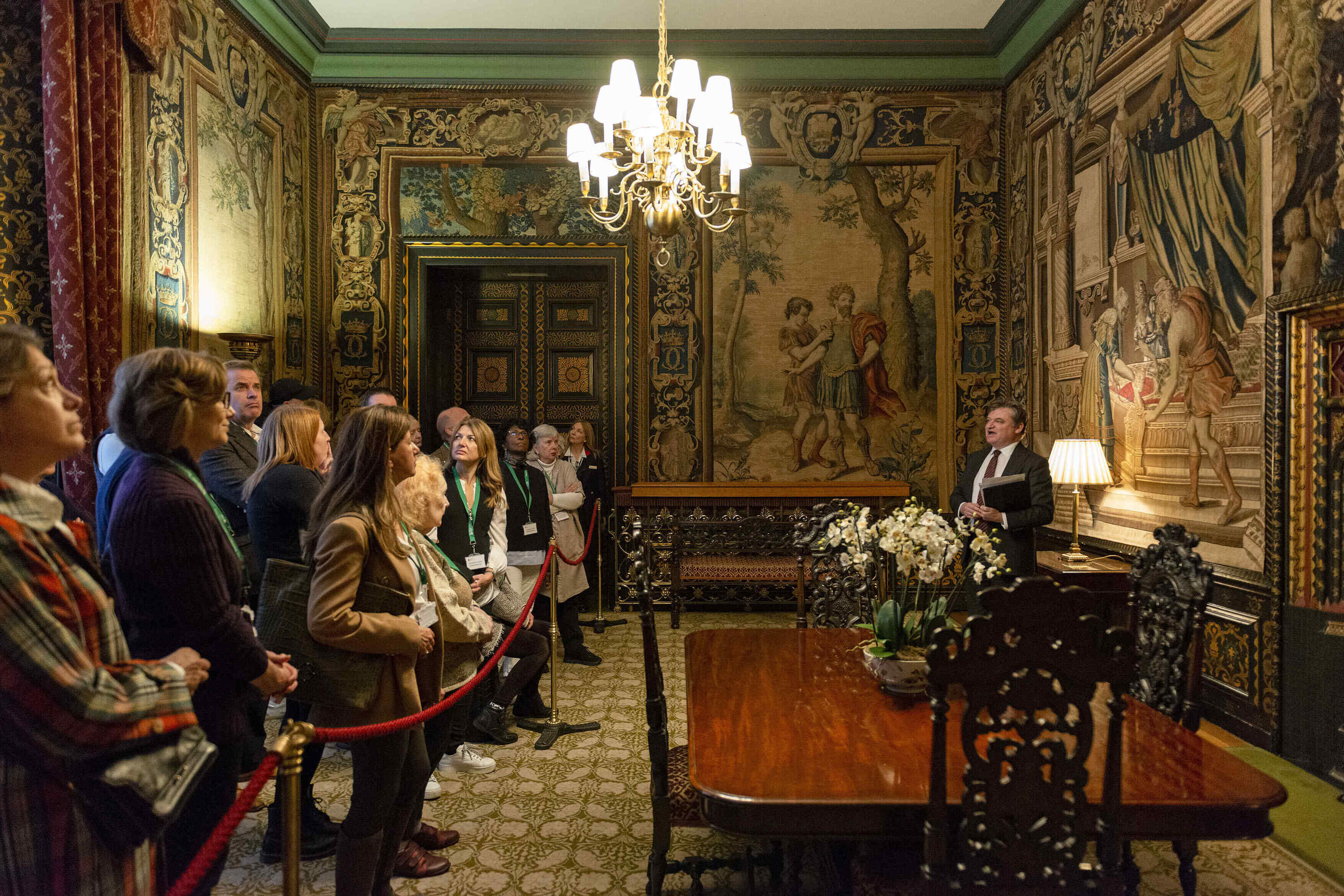 Visitors gather in the Tapestry room of St James's Palace, lit by a large chandelier.