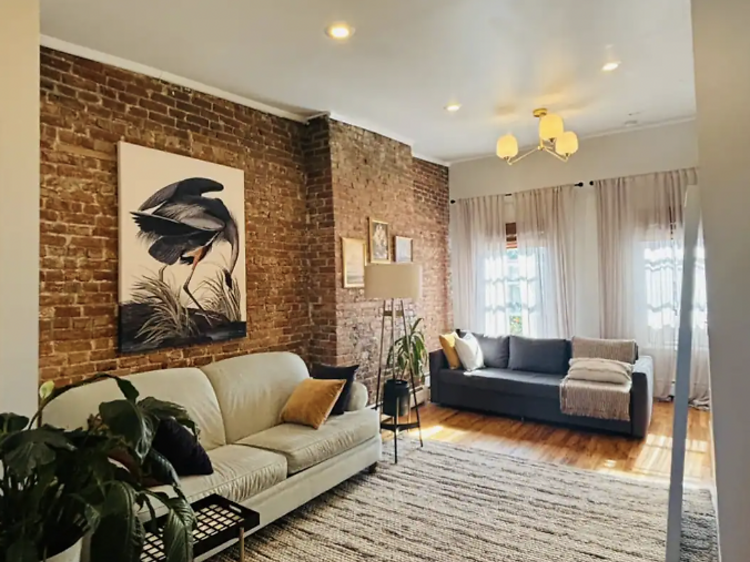 Living room with large rug, sofa and exposed brick feature wall.