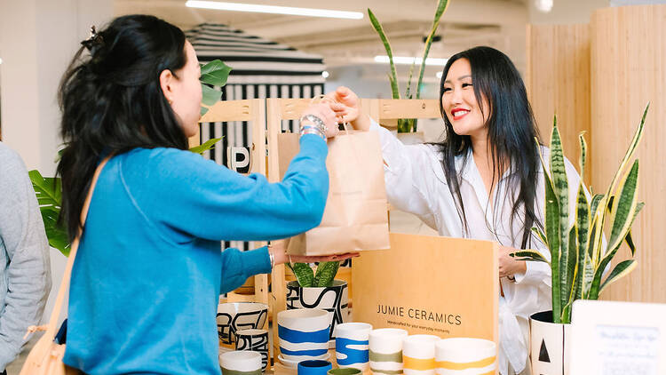 A maker sells ceramic goods to a woman at Unique World.