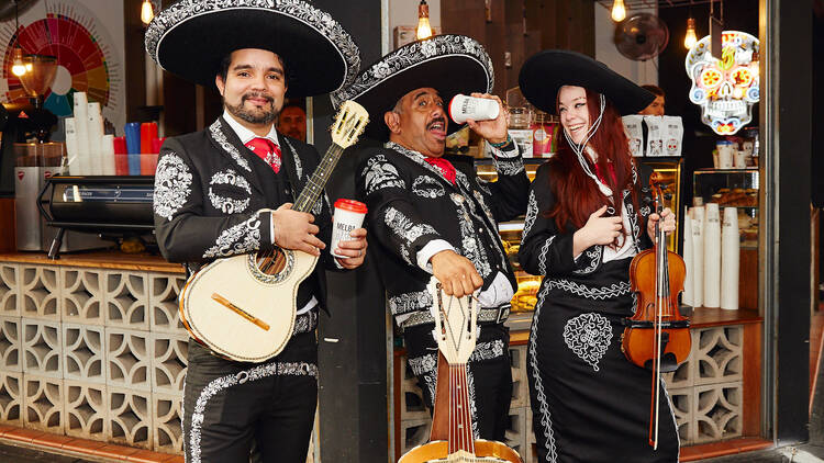 Three people in a mariachi band wearing costumes. 