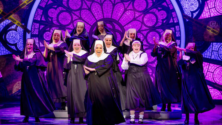 The cast of Sister Act on stage in nun outfits.