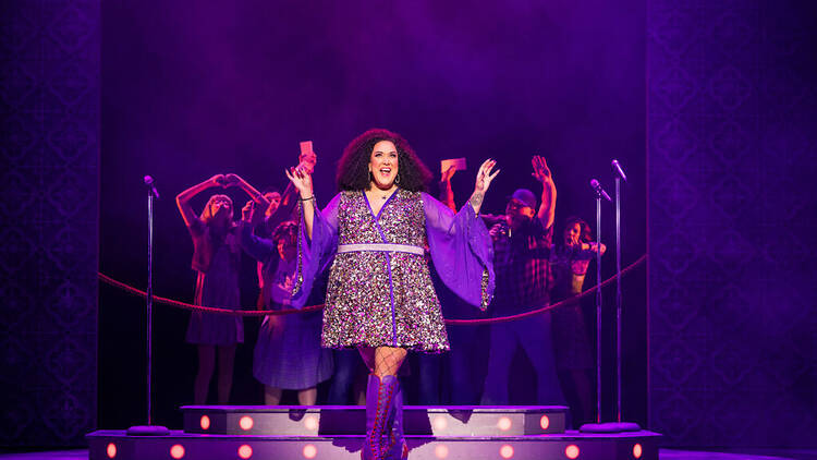 Casey Donovan on stage in a purple disco dress for Sister Act.