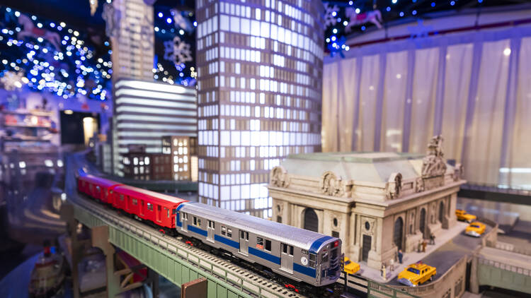 Model trains glide around a track and a model of Grand Central Terminal.