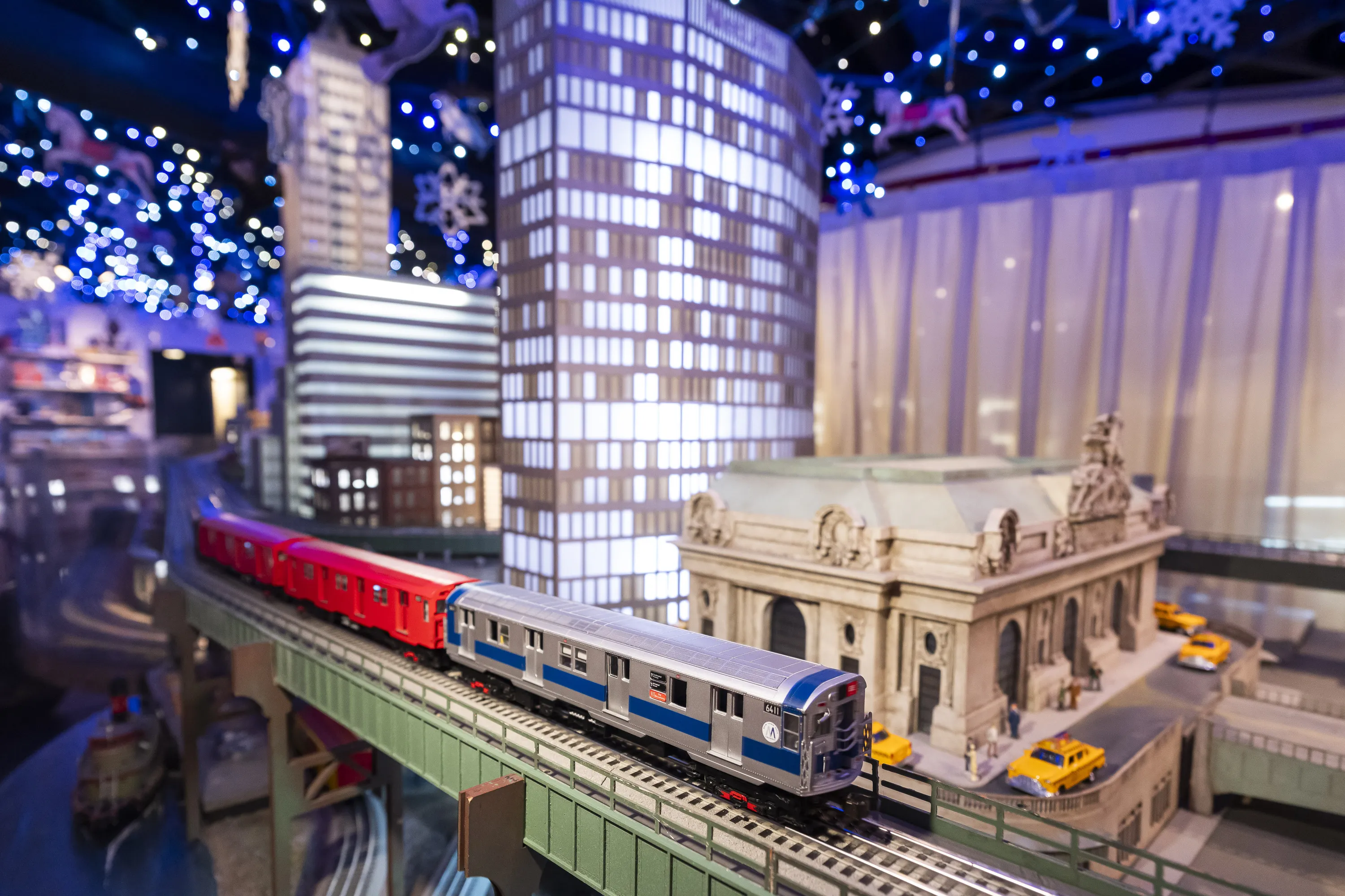 Model trains glide around a track and a model of Grand Central Terminal.