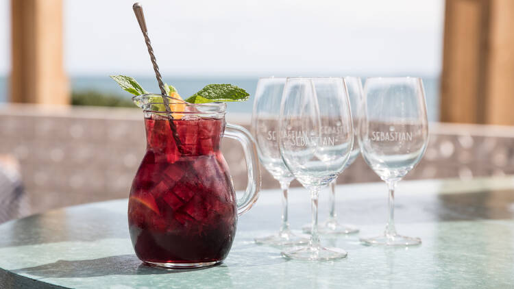 A jug of Sangria and wine glasses on a table at Sebastian Beach Grill and Bar.