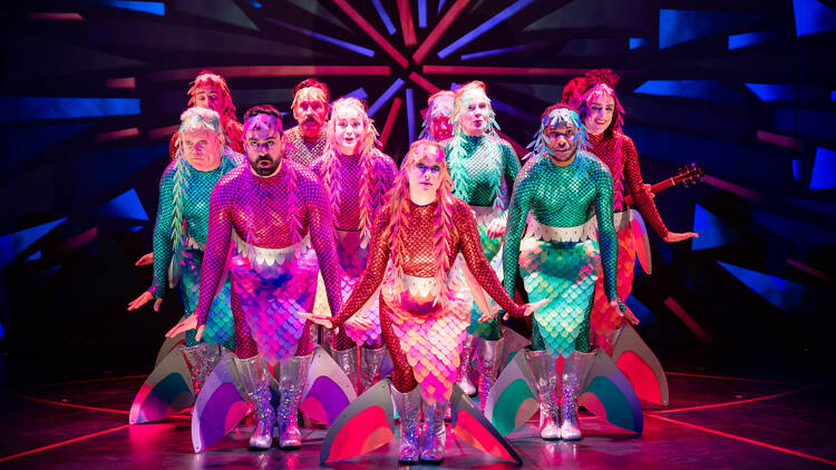 The cast of Peter and the Starcatcher on stage in mermaid outfits.