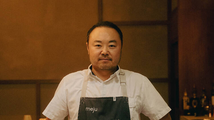 Chef Hooni Kim standing by a wooden counter