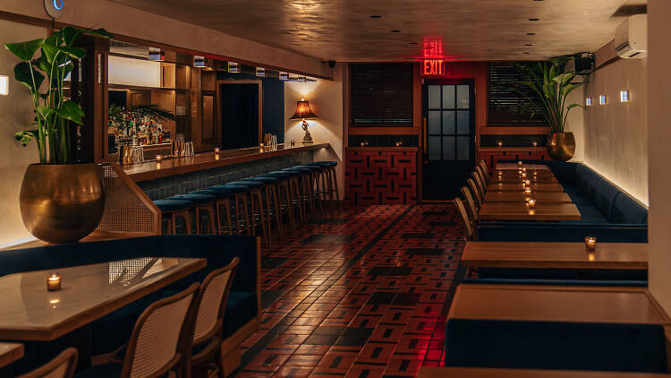 A wooden bar with dark blue stools and booths