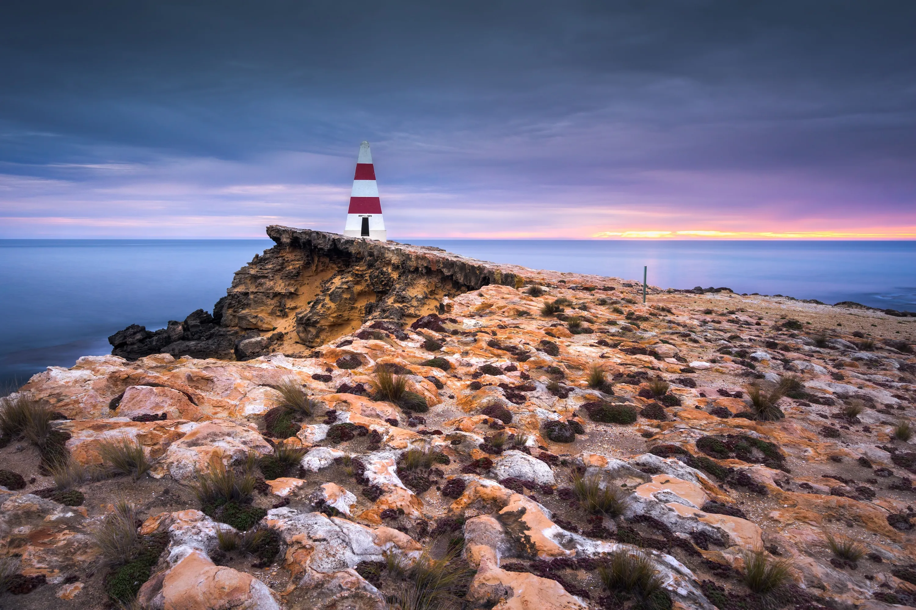 Red and white lighthouse at sunset