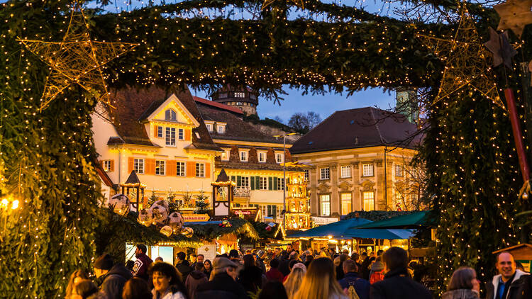 Esslingen am neckar, Germany, December 17, 2019, Entrance gate to christmas market illuminated by night with many people enjoying the beautiful mood