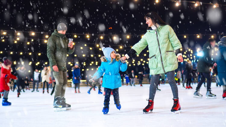 A family ice skating at Holidays on the Hill