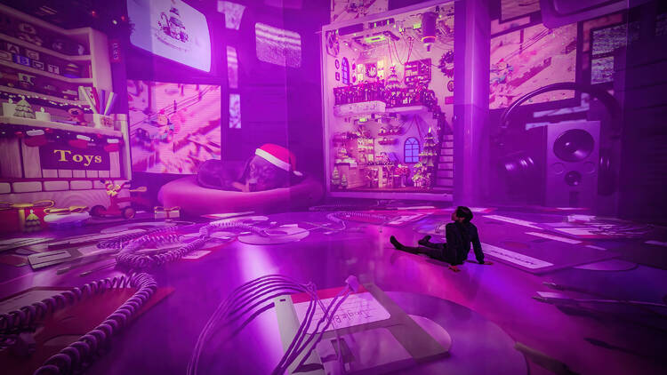 A person sits on the floor inside an immersive exhibit at ARTECHOUSE.