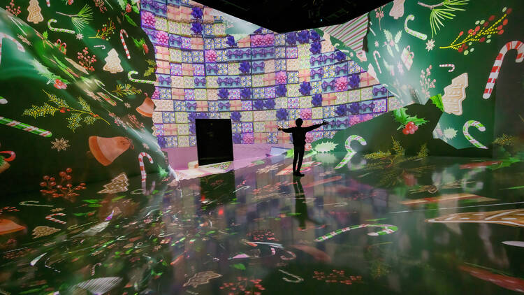 A person outstretches their hands inside an immersive art exhibit.