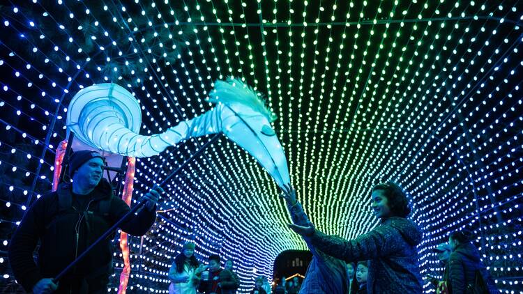 People walk beneath a lit-up archway.