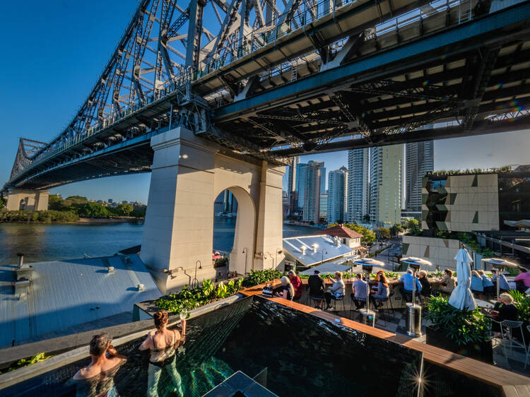 People on rooftop bar under bridge