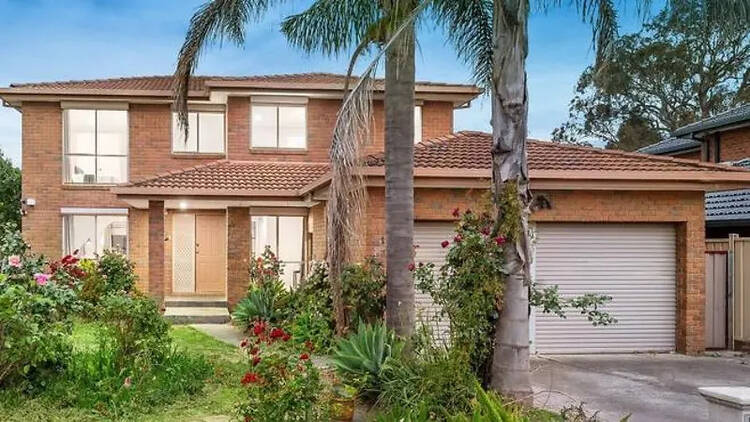 A two storey brick home with a front garden. 