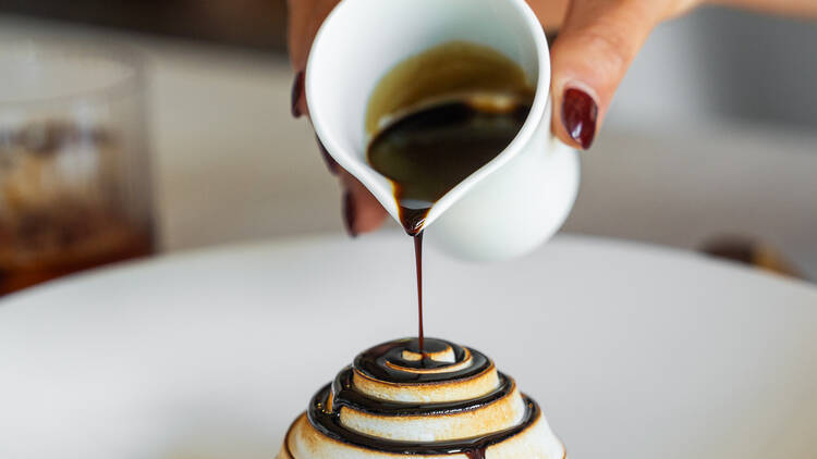 Chocolate sauce being poured over a meringue.