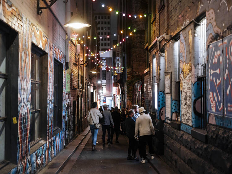 People walking down Tattersalls Lane in Melbourne at night.