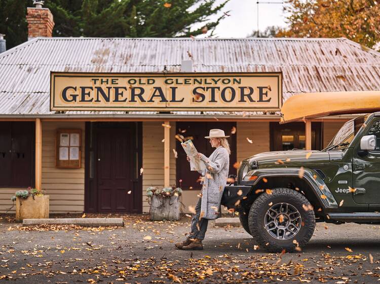 A woman leaning on a car outside the Glenlyon General Store.