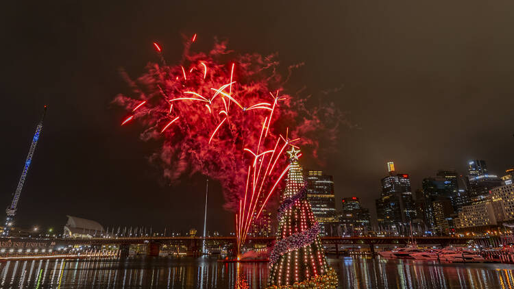 A floating christmas tree in front of fireworks