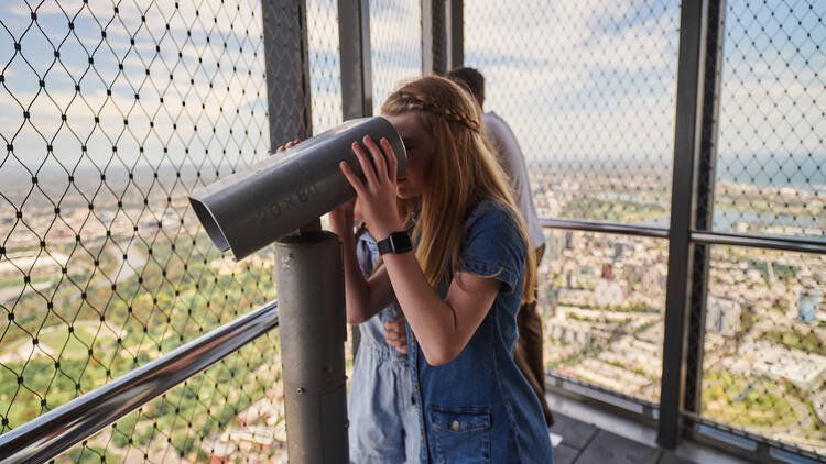 A girl looking through a telescope at Melbourne Skydeck.