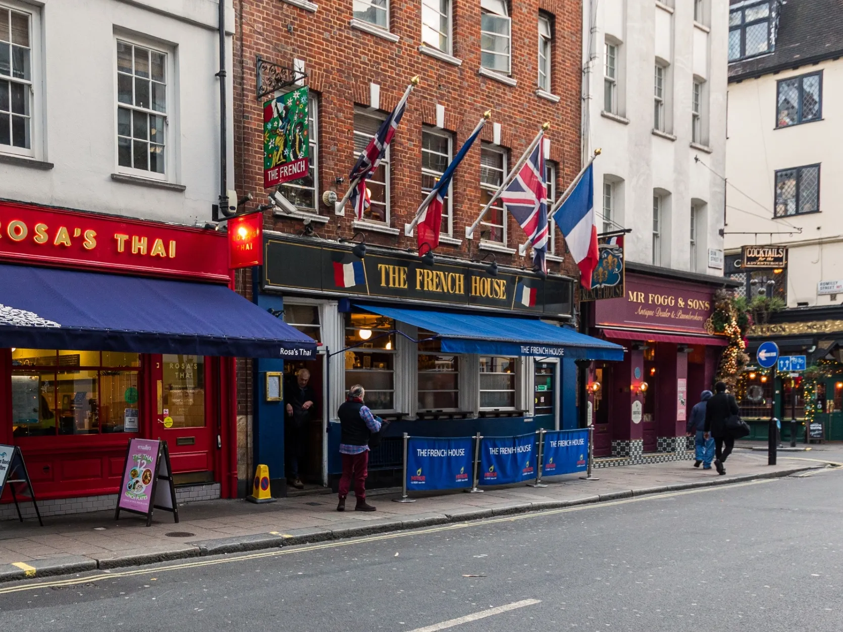 Royal blue awning and matching canvas barriers mark out the smoking area in front of The French House pub in Soho, viewed from the other side of the street