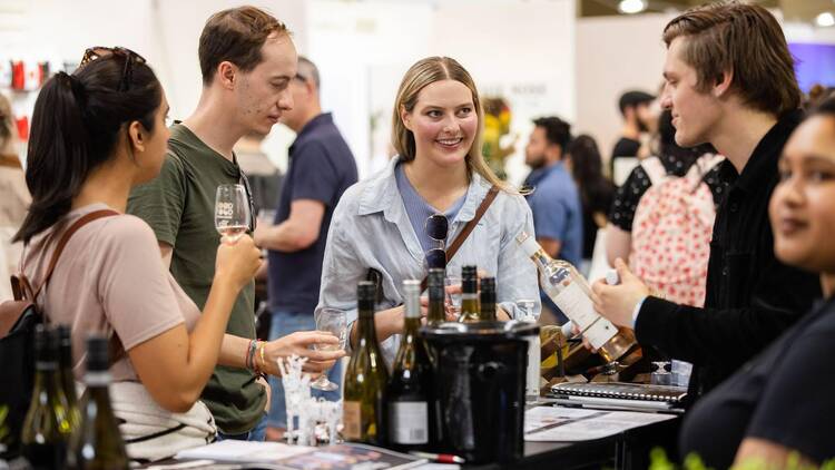 People standing at a table tasting alcohol. 