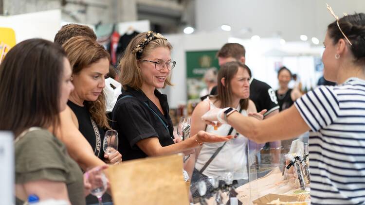 People trying food at a market stall. 