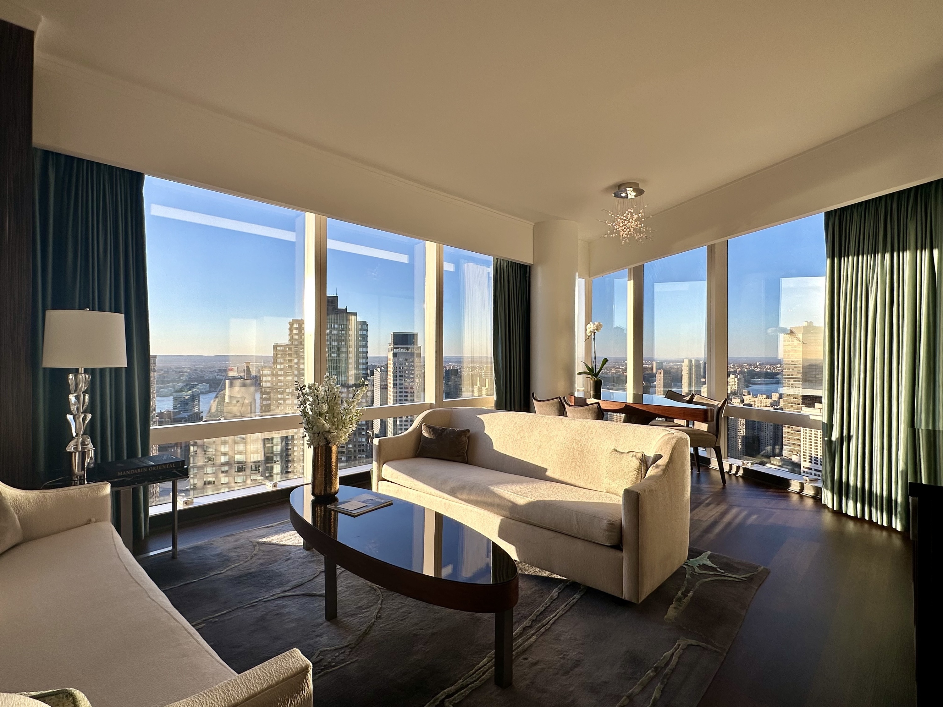 A hotel suite with couches and a table in front of skyline views.
