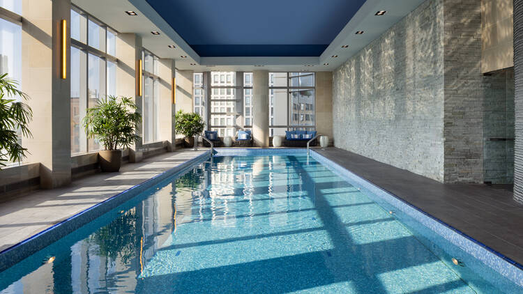 A swimming pool with bright light streaming into the windows.