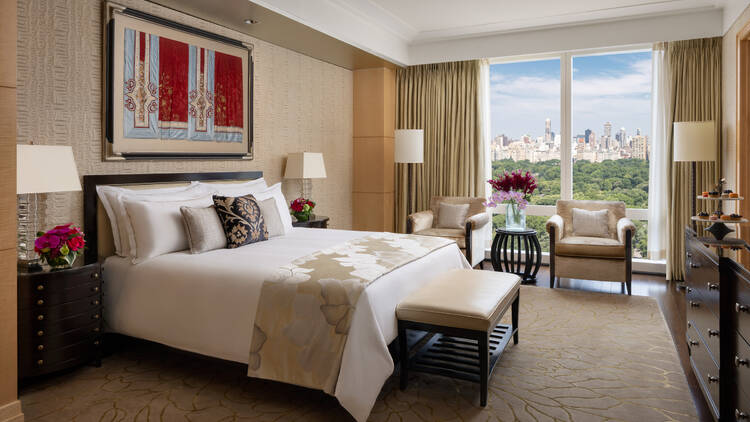 A hotel room with a bed and view of the city.