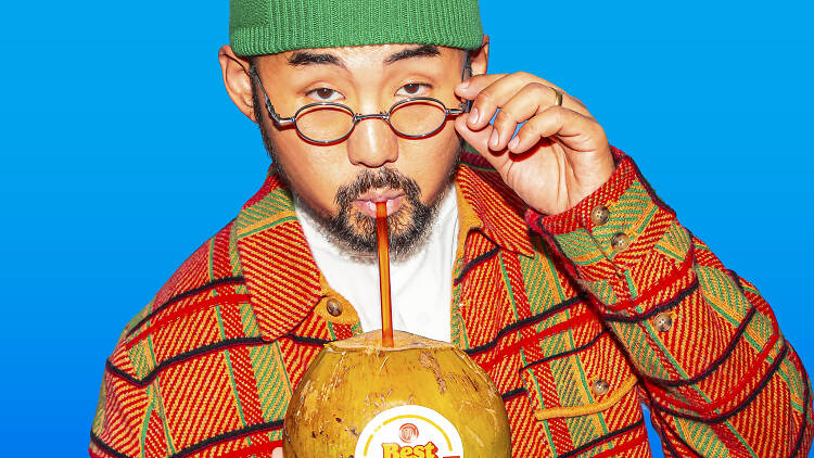 Jaeki Cho holding a bowl of noodles against a blue background