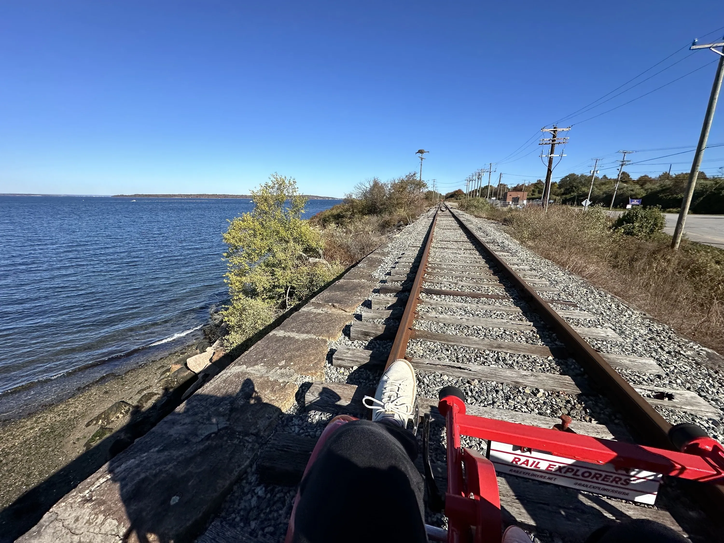 A woman pedals on a rail expolorers bike along railroad tracks.