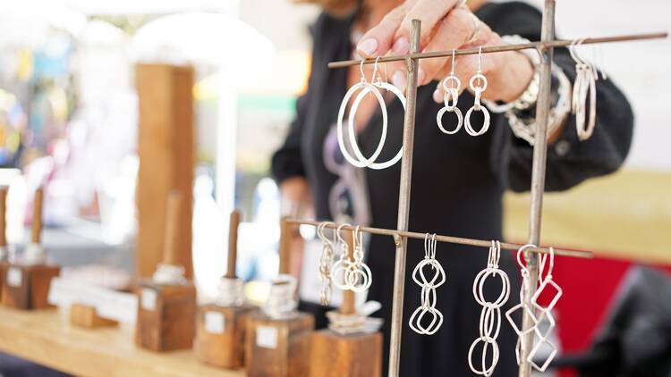 An artisan sells jewelry at a craft fair. 