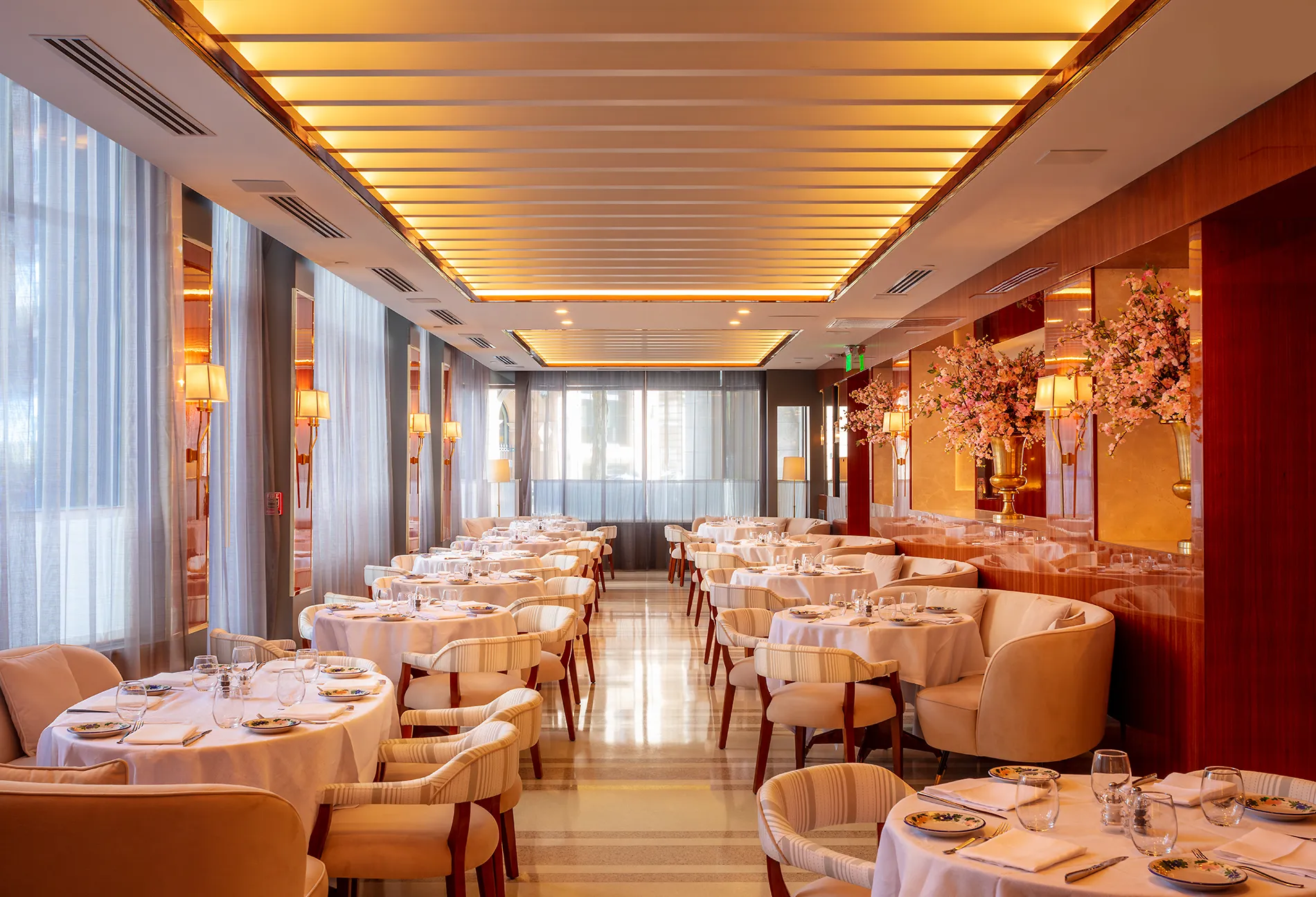 The interior of a restaurant with white tablecloths on tables.