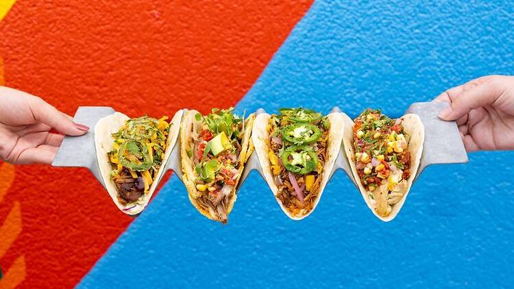 Four tacos on a coloured background