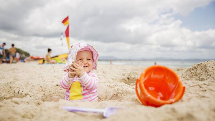 Toddler playing in the sand on Main Beach, Byron Bay.