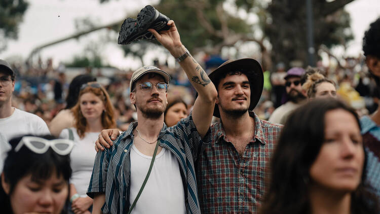 Two people standing together, one is raising a shoe. 