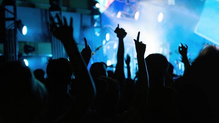 Stock image of a nightclub, strobe lights and arms raised