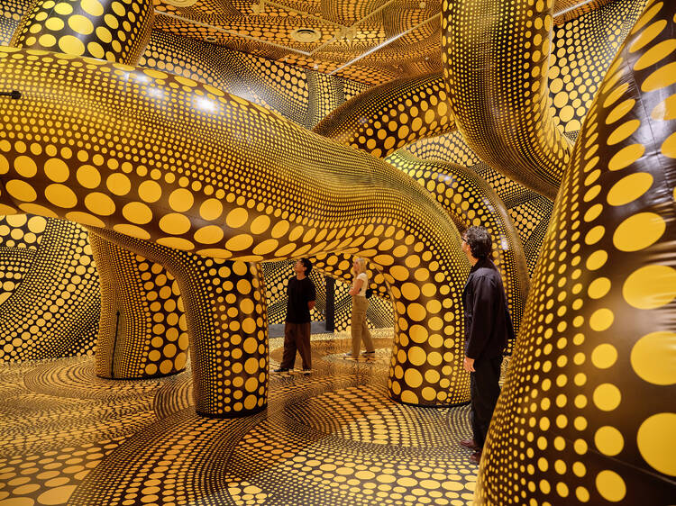 People wandering through a yellow and black room filled with spots.