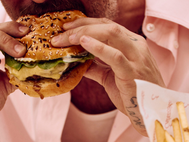 Man eating a cheeseburger with a side of chips.