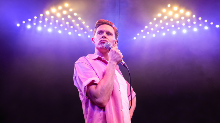 Samuel Barnett on-stage holding a microphone