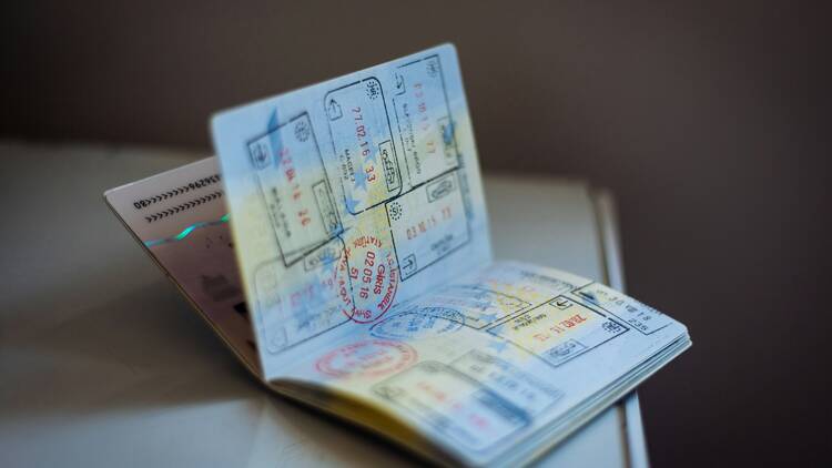 A passport open on a table with stamps