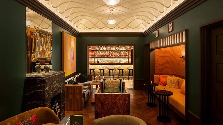 Green walls and a seating area before the bar at Chez Fifi
